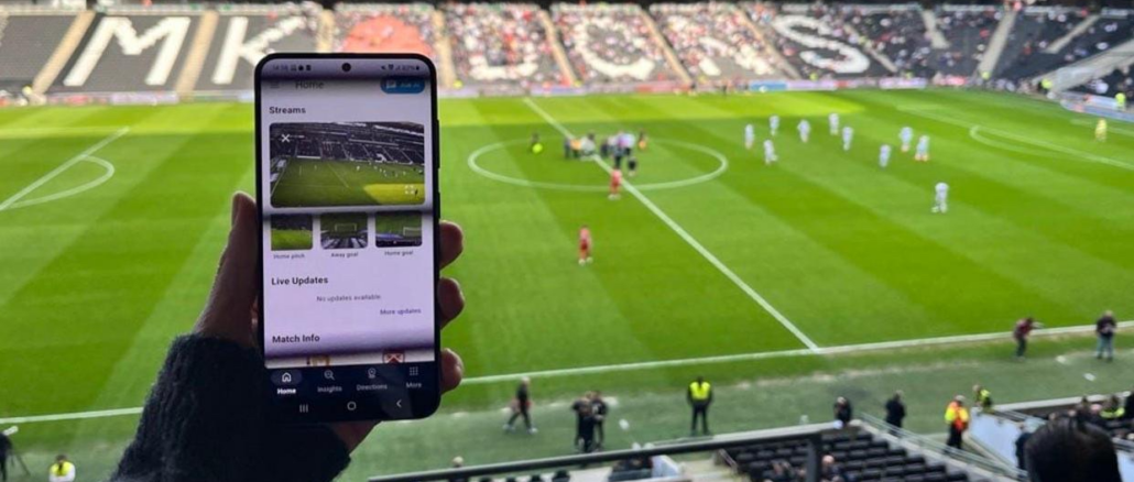 Supporter utilisant son smartphone pendant un match de football illustrant les micro-contenus