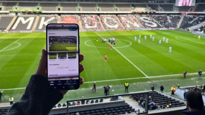 Supporter utilisant son smartphone pendant un match de football illustrant les micro-contenus