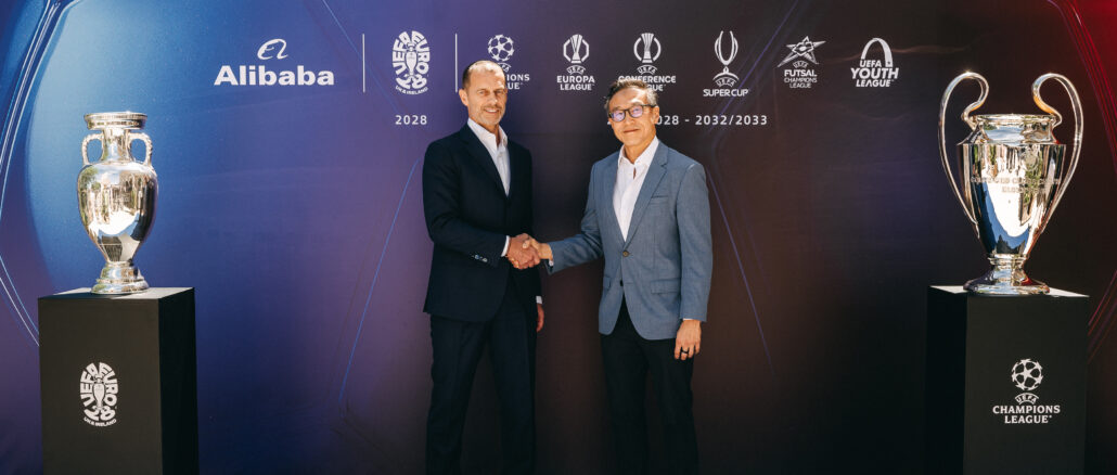 Alibaba UEFA partenariat officiel : Aleksander Čeferin (président de l'UEFA) et Joe Tsai (président d'Alibaba Group) se serrent la main lors de la cérémonie de lancement à Budapest, entourés du trophée Henri Delaunay (EURO 2028) et de la coupe aux grandes oreilles (UEFA Champions League)