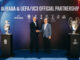 Alibaba UEFA partenariat officiel : Aleksander Čeferin (président de l'UEFA) et Joe Tsai (président d'Alibaba Group) se serrent la main lors de la cérémonie de lancement à Budapest, entourés du trophée Henri Delaunay (EURO 2028) et de la coupe aux grandes oreilles (UEFA Champions League)