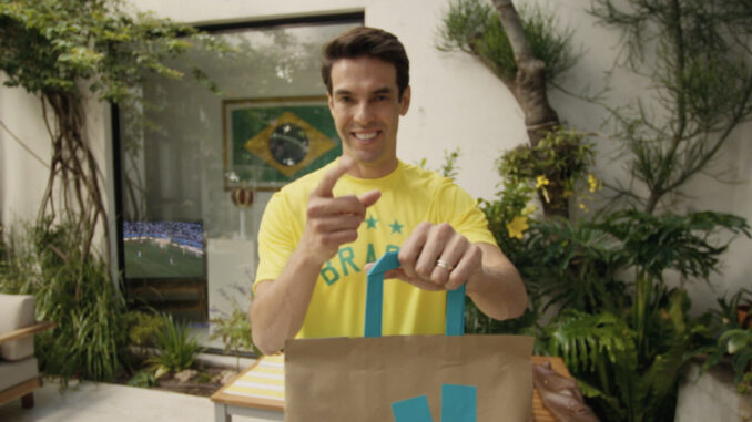 Ricardo Kaká en maillot du Brésil pointant un sac Deliveroo devant un écran diffusant un match de football pour la campagne Coupe du Monde 2026