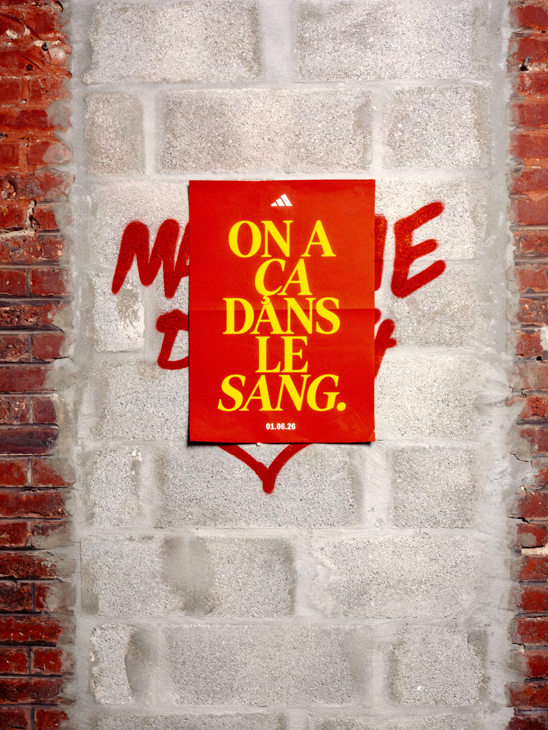 Affiche de la campagne adidas On a ça dans le sang pour le RC Lens collée sur un mur en briques rouges
