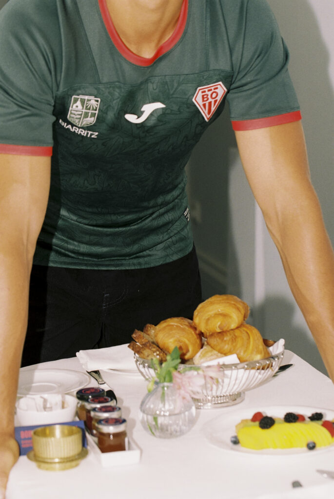 Maillot extérieur du Biarritz Olympique porté avec un pantalon de costume devant un chariot de petit-déjeuner