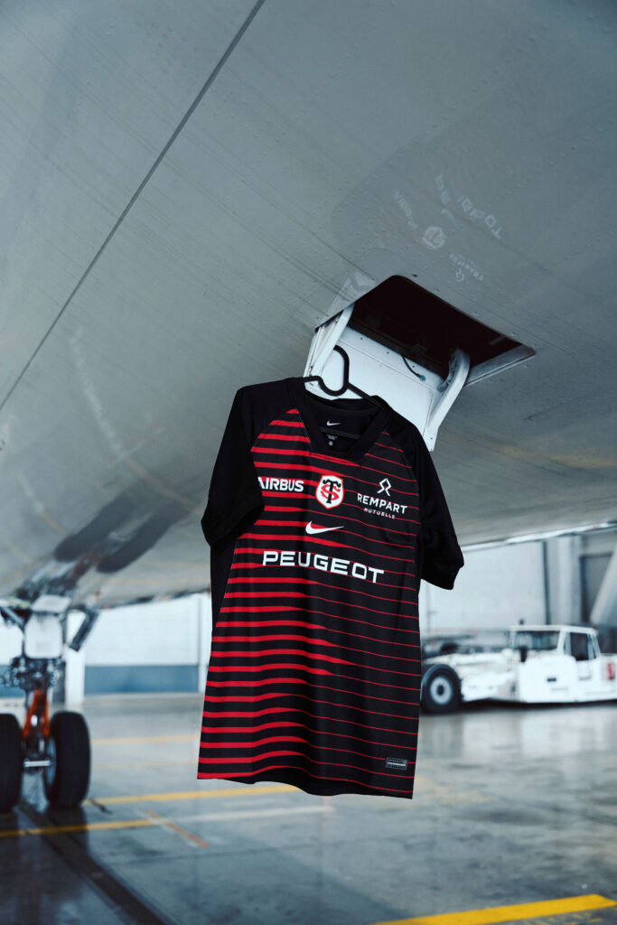 Maillot domicile 2026-2027 du Stade Toulousain suspendu sous le fuselage d'un avion dans un hangar Airbus