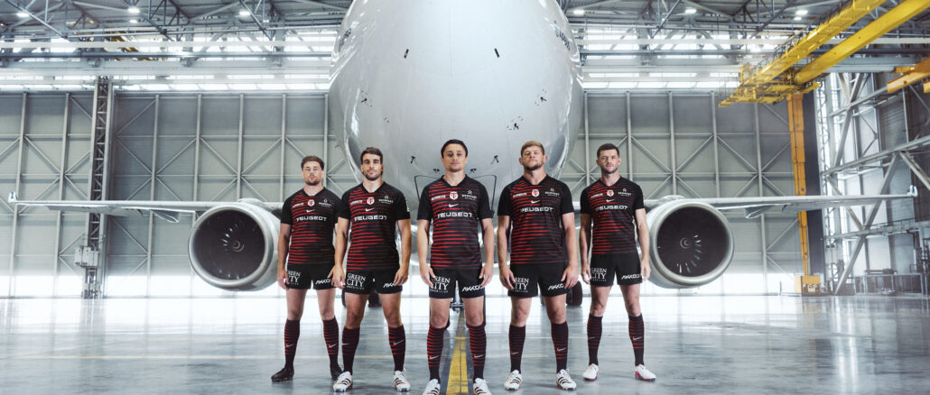 Joueurs du Stade Toulousain en maillot domicile 2026-2027 devant un A330neo dans les installations d'Airbus