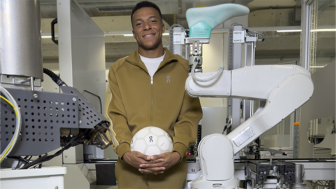 Kylian Mbappé tient un ballon On devant un bras robotisé au On Labs Zurich