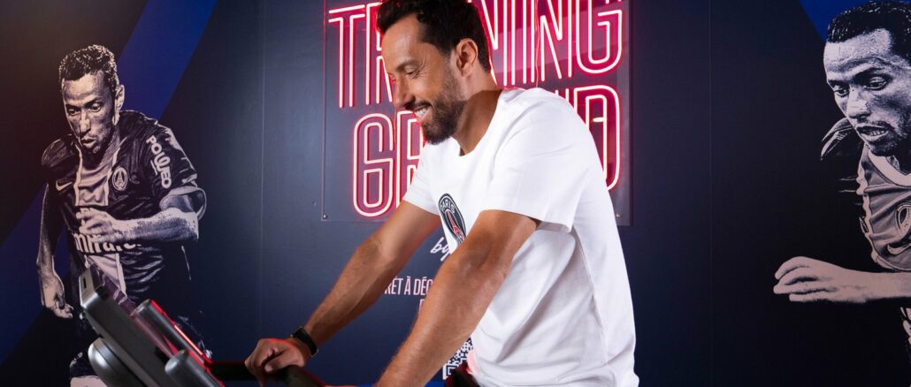 Nenê, légende du PSG, sur un vélo d'appartement dans l'espace fitness Training Ground d'un hôtel Novotel