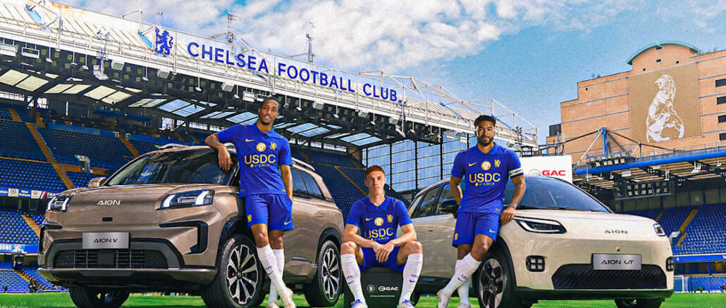 Trois joueurs de Chelsea posent avec deux voitures AION de GAC sur la pelouse de Stamford Bridge