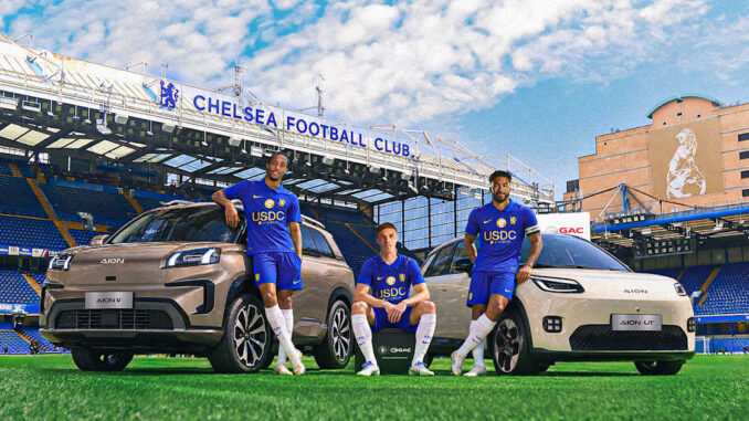 Trois joueurs de Chelsea posent avec deux voitures AION de GAC sur la pelouse de Stamford Bridge