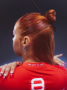 Jeune femme de dos portant le maillot third du Stade Toulousain, signature The City Is Ours sous le col
