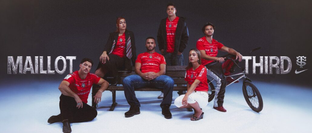 Joueurs du Stade Toulousain et jeunes Toulousains posant autour d'un banc public avec le maillot third rouge 2026-2027