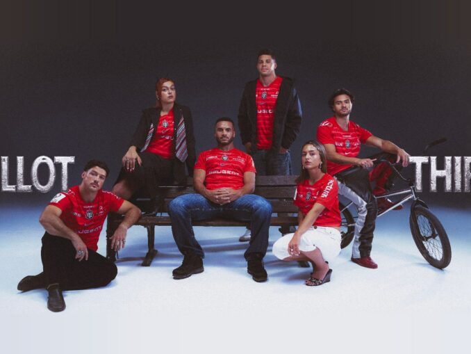 Joueurs du Stade Toulousain et jeunes Toulousains posant autour d'un banc public avec le maillot third rouge 2026-2027