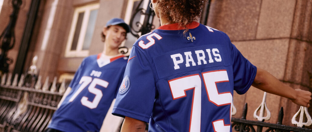Deux jeunes portant le maillot de football américain PSG × NFL Paris Red & Blue, floqué PARIS 75, dans une rue parisienne