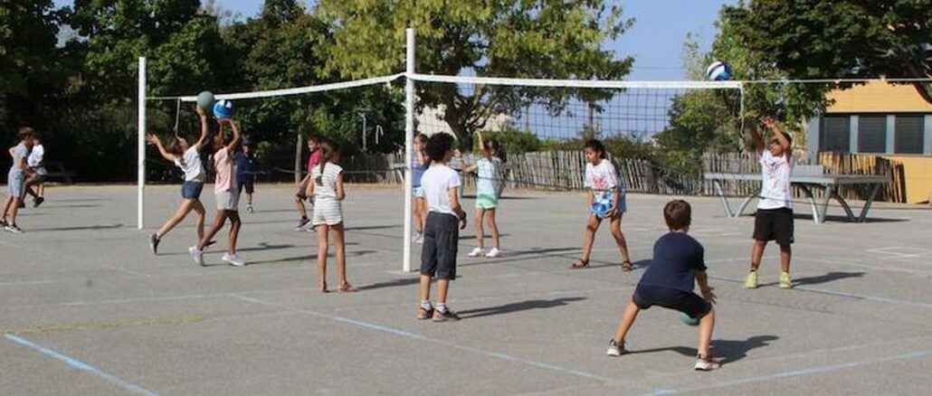 Des écoliers jouent au volley de part et d'autre d'un filet dans une cour d'école, lors d'une séance Smashy