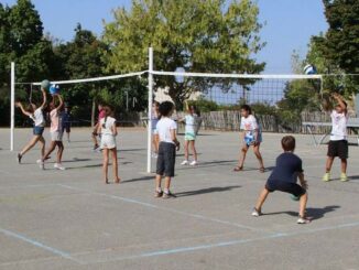 Des écoliers jouent au volley de part et d'autre d'un filet dans une cour d'école, lors d'une séance Smashy
