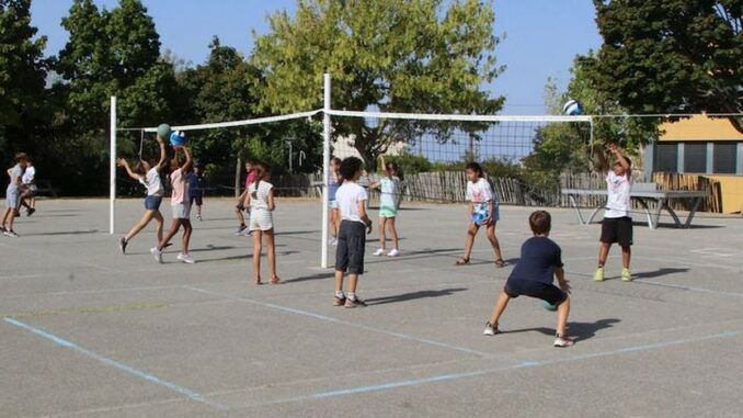 Des écoliers jouent au volley de part et d'autre d'un filet dans une cour d'école, lors d'une séance Smashy